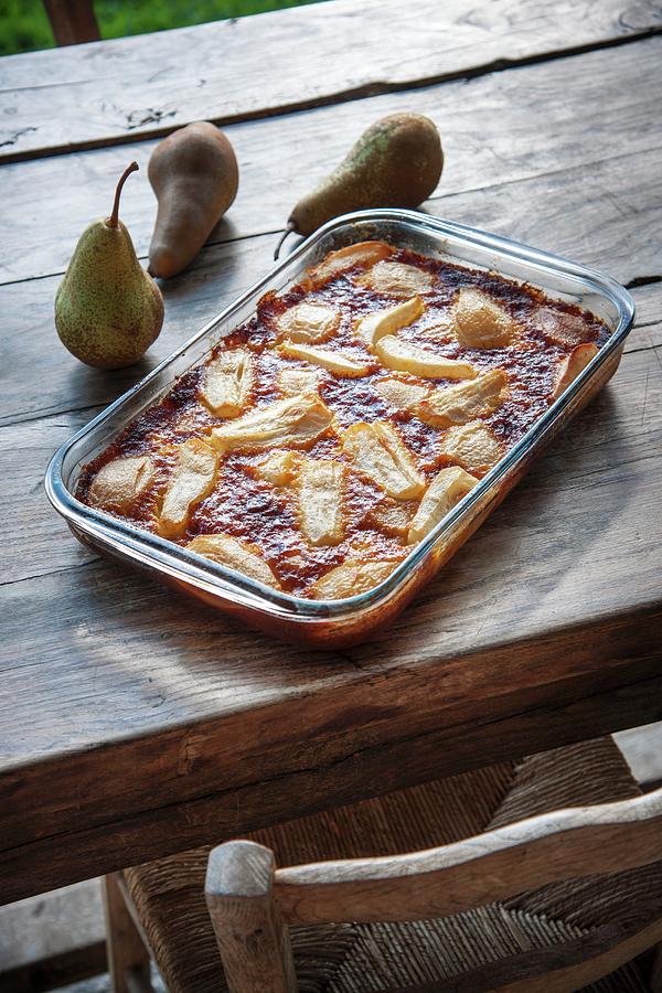 Pear Clafoutis In The Baking Dish On A Wooden Table Photograph by Christophe Madamour