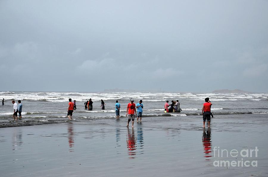 People and families wade in water and enjoy the waves at Sea View beach Karachi Pakistan Photograph by Imran Ahmed
