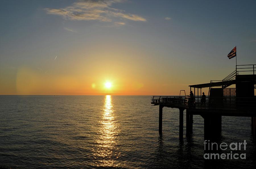 People enjoy sunset over Black Sea horizon at pier with flag Batumi Georgia by Imran Ahmed People enjoy sunset over Black Sea horizon at pier with flag Batumi Georgia by Imran Ahmed