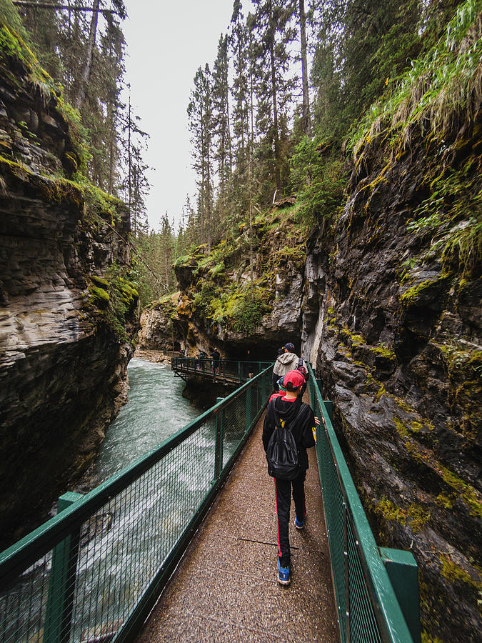 Banff National Park Photograph - People Walking On Metal Catwalk Alongside The Flowing Water In Canyon. by Cavan Images