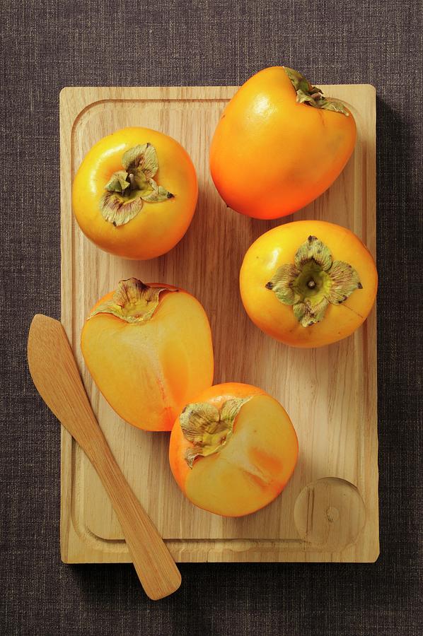 Persimmons, Whole And Halved Photograph by Jean-christophe Riou