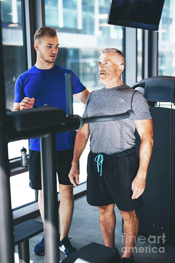Personal trainer giving instructions to older man at the gym Photograph by Michal Bednarek