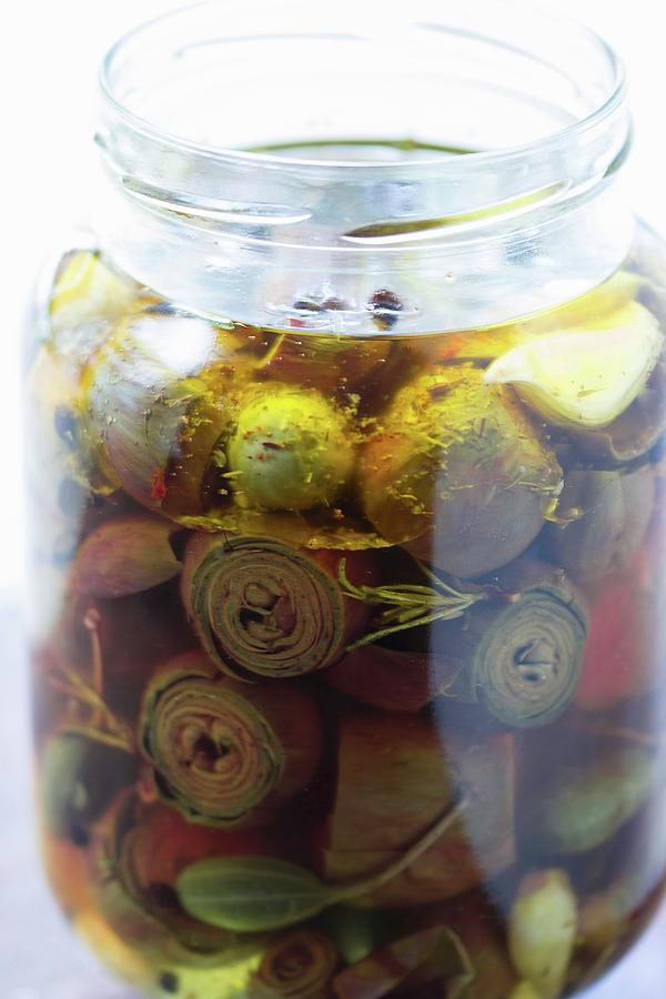 Pickled Baby Artichokes In A Jar With Caper Fruits, Bay Leaves And Rosemary Photograph by Charlotte Von Elm