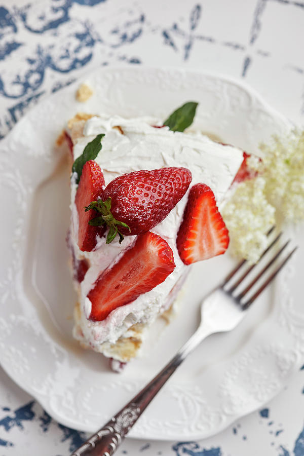 Piece Of Pavlova Cake With Fresh Strawberries Garnished With Mint Leaves And Elderflower Photograph by Natasa Dangubic