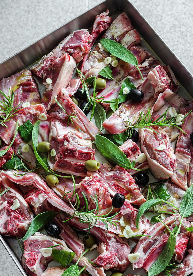 Pieces Of Raw Lamb With Garlic, Olives, Sage, Rosemary And Bay Leaves On A Baking Tray Photograph by Giulia Verdinelli Photography