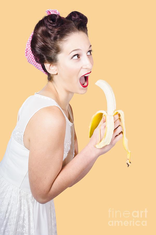 Pin-up woman eating fruit on studio background Photograph by Jorgo Photography