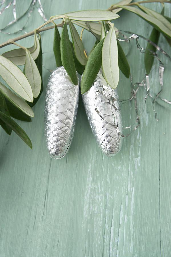 Pine Cones Covered In Silver Foil And Lametta Hanging From Olive Branch Photograph by Martina Schindler