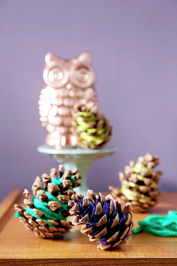 Pine Cones Wrapped In Colourful Thread In Front Of Owl Ornament Photograph by Thordis Rggeberg