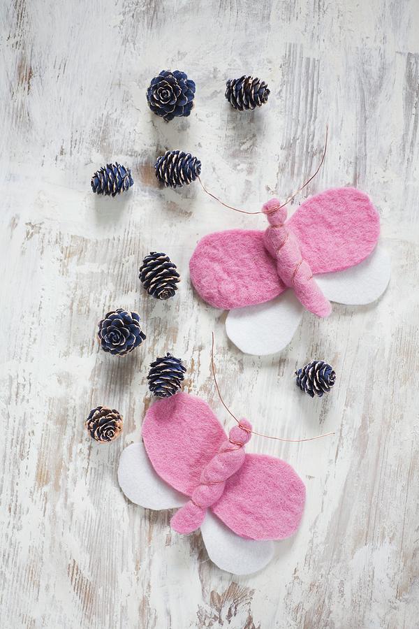 Pink And White, Hand-made Felt Butterflies And Blue-painted Pine Cones Arranged On Vintage Wooden Surface Photograph by Alicja Koll