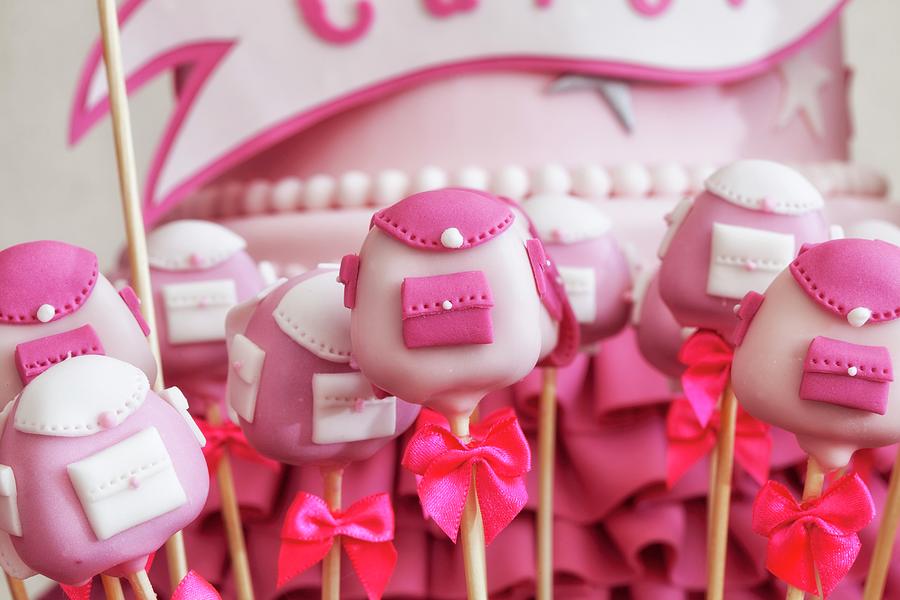 Pink Cake Pops Shaped Like Schoolbags With A Pink Cake In The Background Photograph by Karl Stanzel