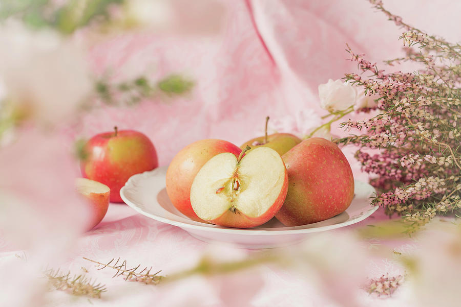 Pink Lady Apples On A Plate, Pink Flowers On A Pastel Colored Background Photograph by Albina Bougartchev