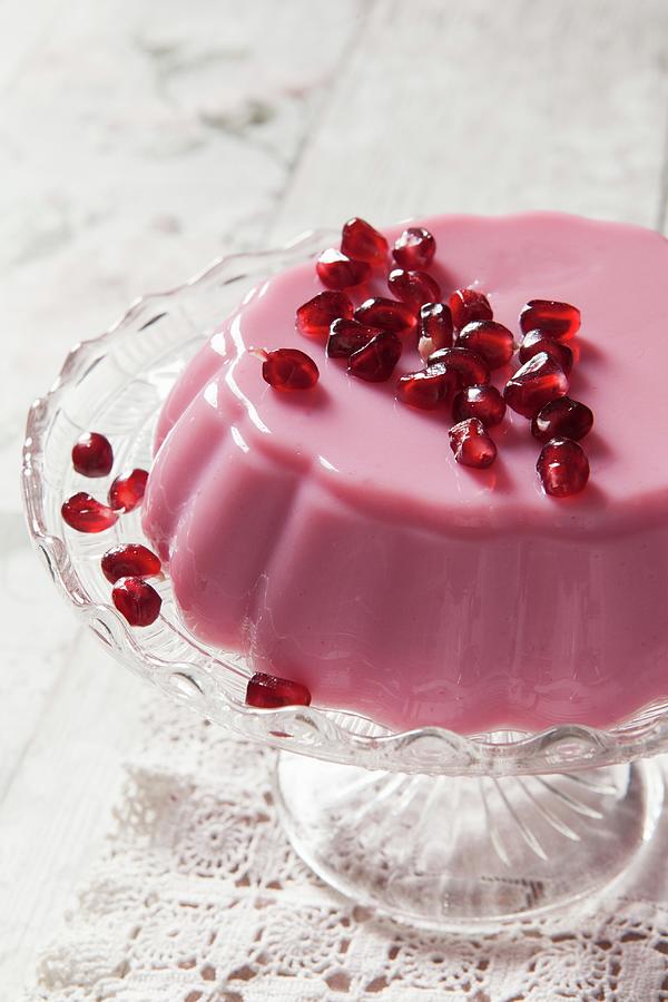 Pink Milk Jelly Covered In Pomegrante Seeds On A Glass Cake Stand And Vintage Lace Tablecloth Photograph by Stacy Grant