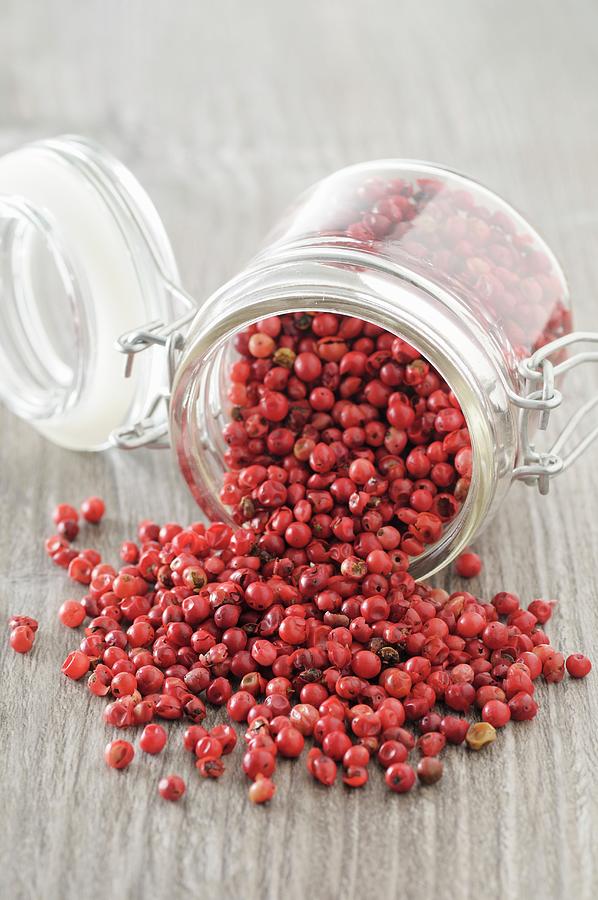 Pink Peppercorns Falling From An Overturned Jar Photograph by Jean-christophe Riou