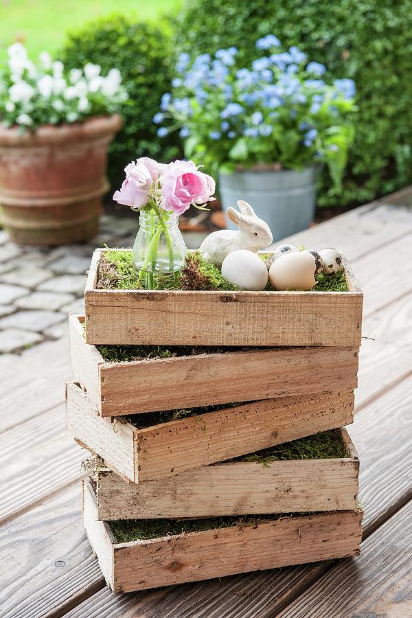 Pink Posy In Glass Vase And Easter Decorations In Stacked Wooden Crates On Wooden Terrace Photograph by Moog & Van Deelen