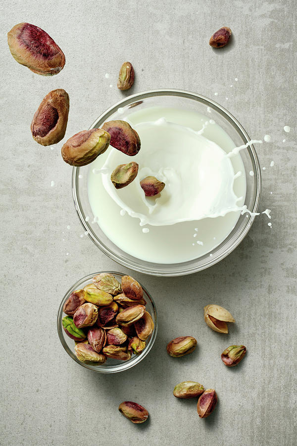 Pistachios Falling Into A Glass Of Milk Photograph by Petr Gross