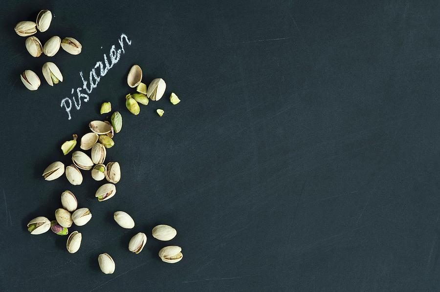Pistachios, Whole And Hulled, Arranged Around The German Word For Pistachios Written In Chalk On A Blackboard Photograph by Achim Sass