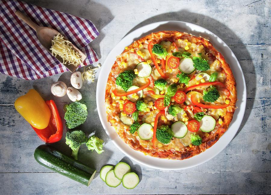 Pizza With Courgette, Broccoli, Mushroom And Peppers With A Tea Towel On A Light Wood Surface Photograph by Julian Winkhaus