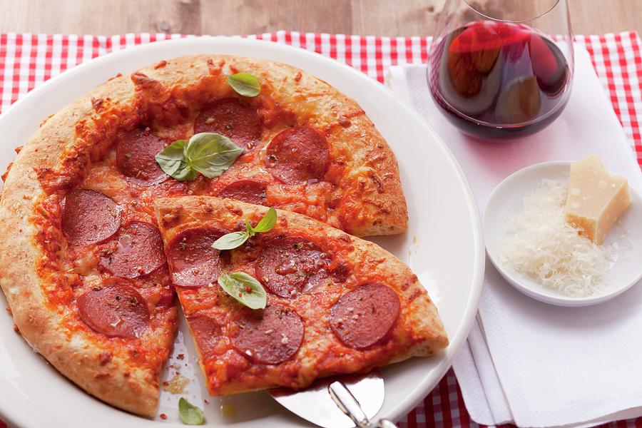 Pizza With Salami And Basil; One Slice Of The Pizza Is On A Pizza Shovel Photograph by Foodcollection