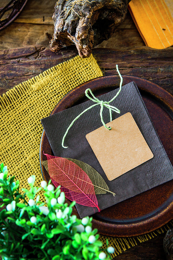 Place Setting With A Card And Leaf Decorations On A Rustic Wooden Table Photograph by Mythja