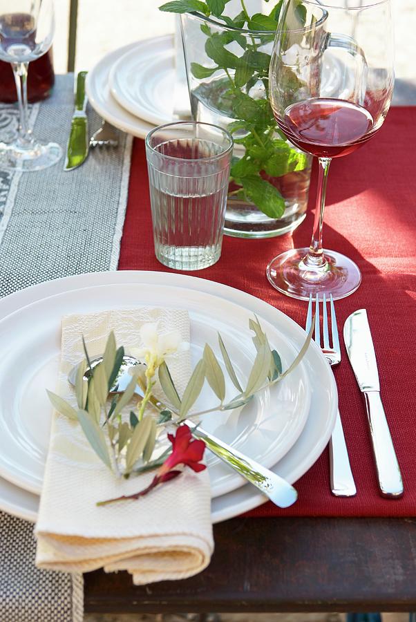 Place Settings With Olive Sprig And Flower On Red Tablecloth Photograph by Hsfoto