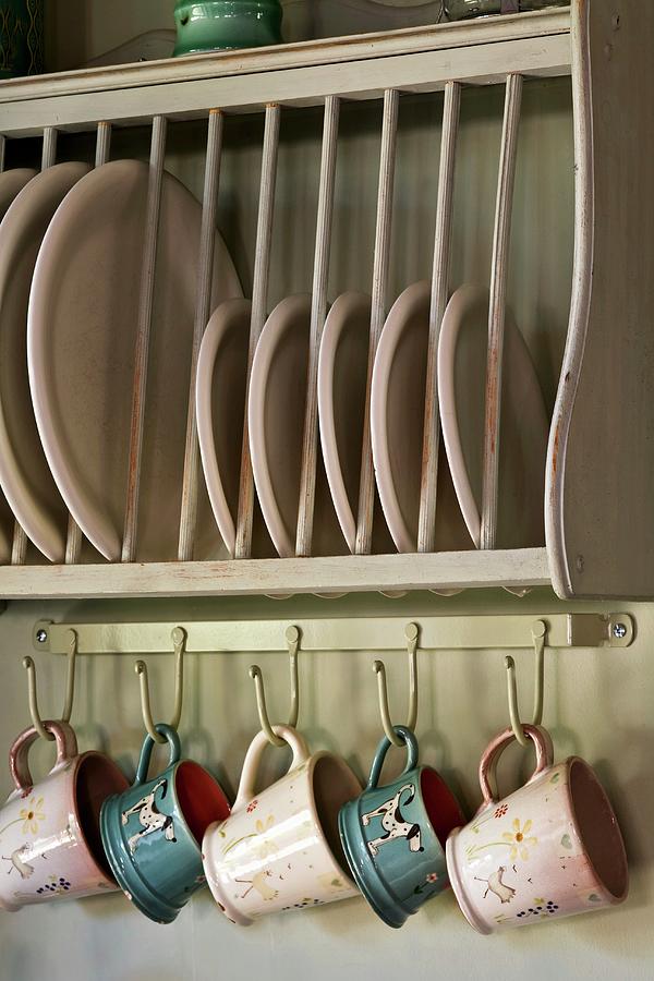 Plates In Rack And Cups Hanging On Hooks Photograph by Steven Morris