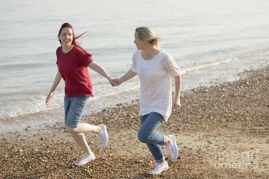 Playful Lesbian Couple Holding Hands And Running Photograph By Caia 