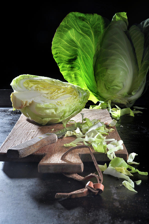 Pointed Cabbage, Whole, Halved And Sliced, On A Chopping Board With A Knife On A Black Baking Tray Photograph by Christoph Maria Hnting