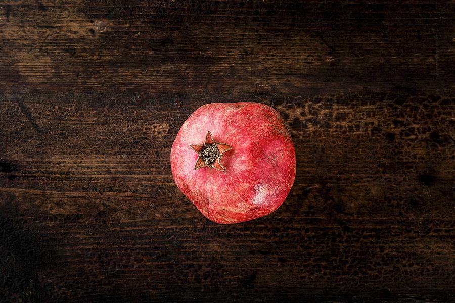 Pomegranate On A Wooden Surface Photograph by Sarah Coghill