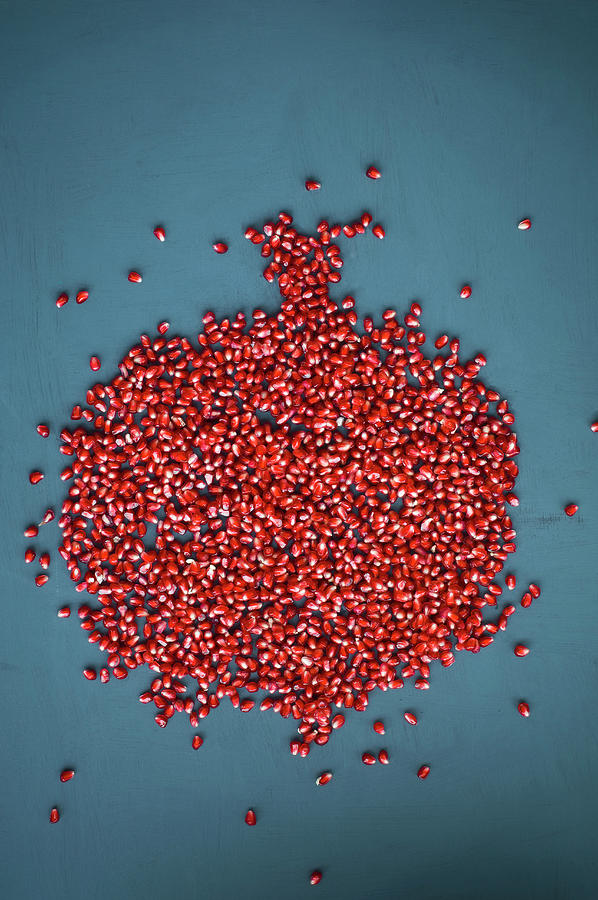 Pomegranate Seeds Arranged In The Shape Of A Pomegranate On A Blue Background Photograph by Achim Sass