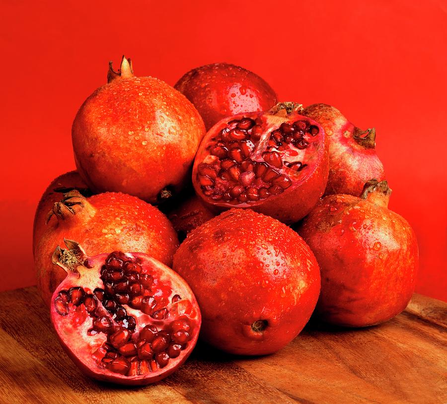 Pomegranates And Two Pomegranate Halves Against A Red Background Photograph by Robert Morris