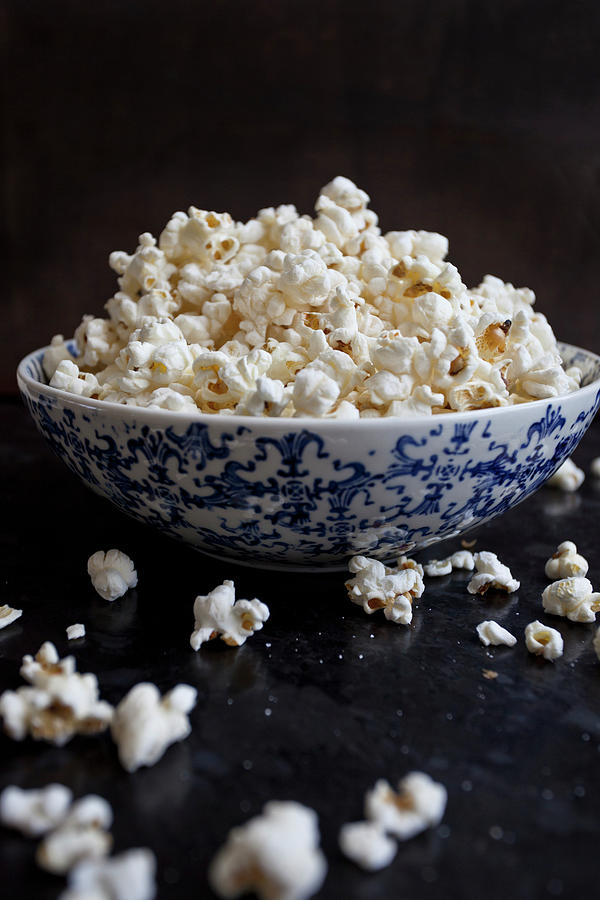 Popcorn In A Blue And White Bowl, Spilling Onto A Black Countertop Photograph by Ryla Campbell