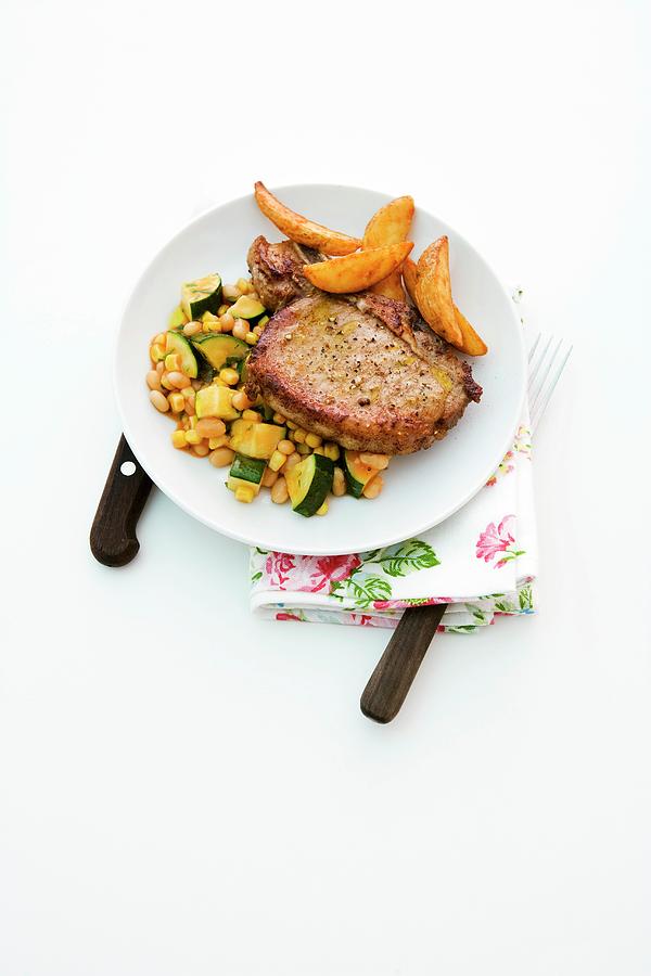 Pork Chops With Baked Beans, Courgette And Potato Wedges Photograph by Michael Wissing
