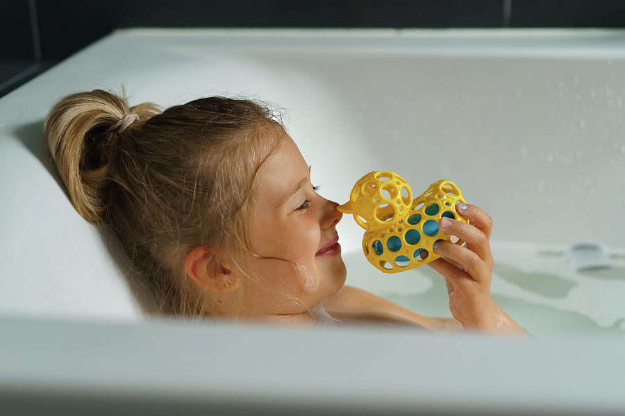 Portrait Photograph - Portrait Of A Smiling Young Girl In Bath With A Rubber Duck. by Cavan Images