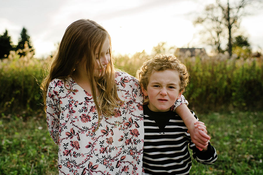 Nature Photograph - Portrait Of Brother Making Face While Standing By Sister At Park by Cavan Images