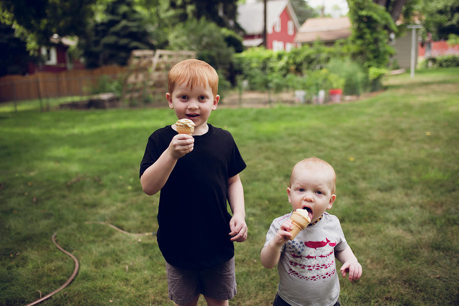 Ice Cream Photograph - Portrait Of Brothers Eating Ice Cream Cones While Standing On Grassy Field At Park by Cavan Images