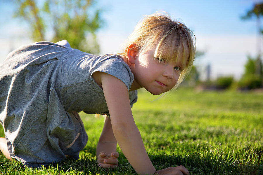 Portrait Of Girl Kneeling On Field At Park Photograph by Cavan Images ...