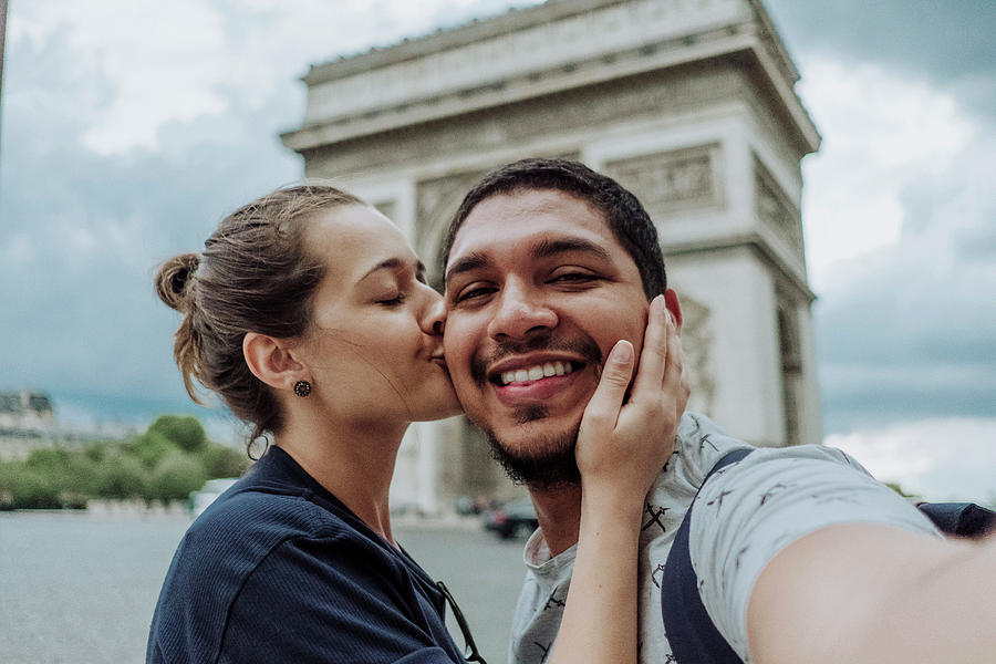 Portrait Of Girlfriend Kissing Smiling Boyfriend Against Arc De ...