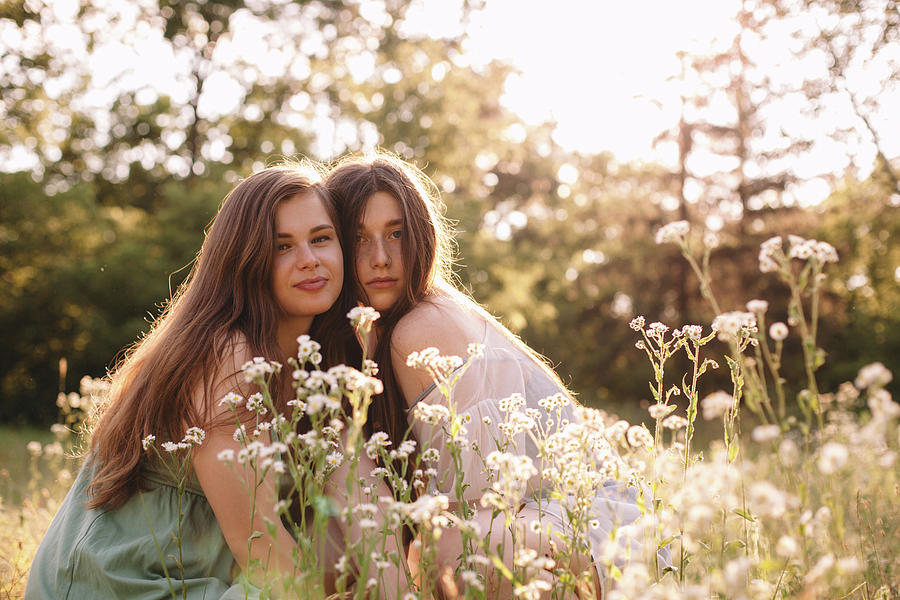 Portrait Of Lesbian Couple Sitting Amidst Flowers In Summer Forest Photograph By Cavan Images