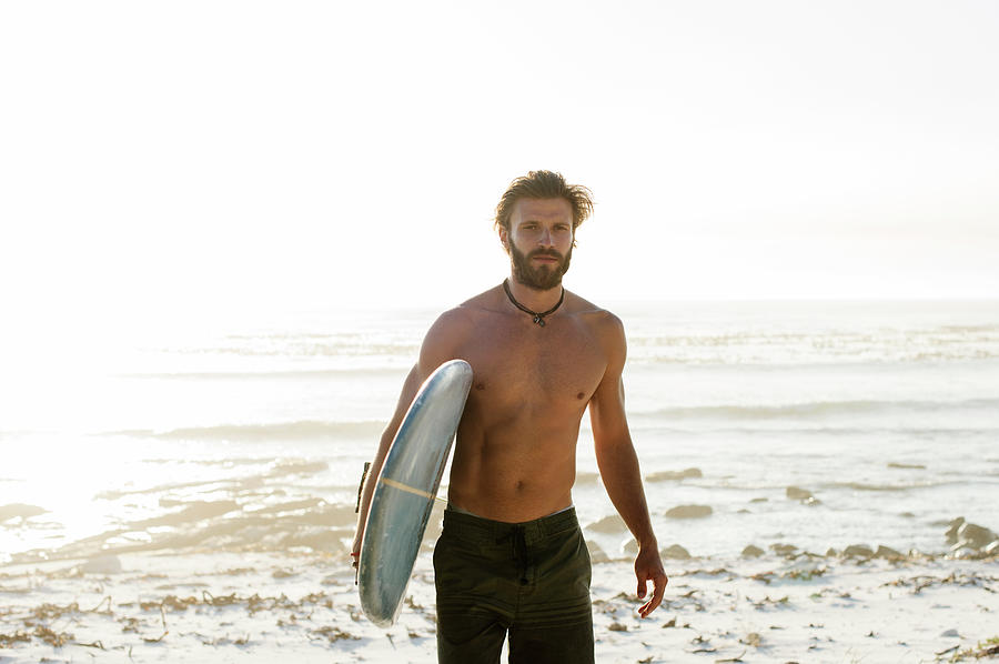 Portrait Of Shirtless Man Carrying Surfboard While Walking At Beach ...