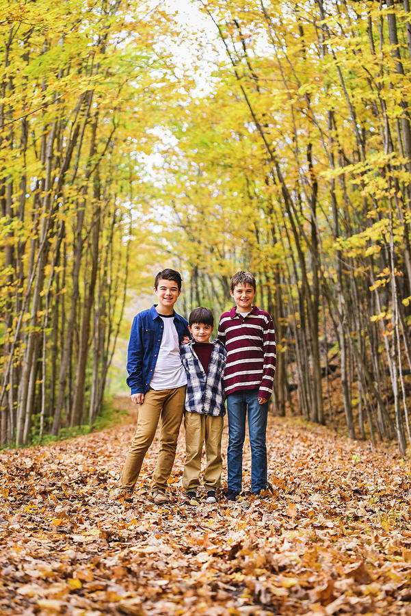 Tree Photograph - Portrait Of Smiling Brothers Standing On Dry Leaves In Forest During Autumn by Cavan Images