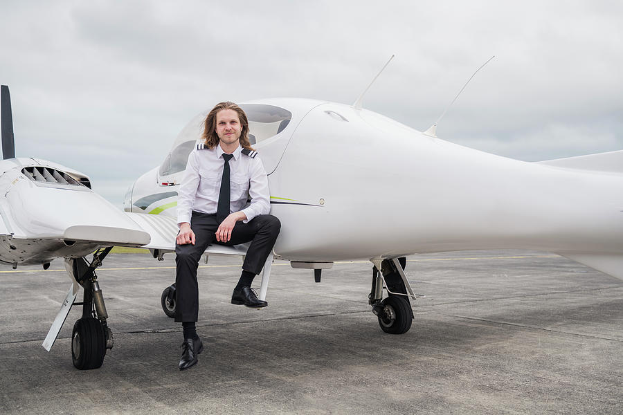 Portrait Of Smiling Male Pilot Standing On Airplane At Airport Runway ...