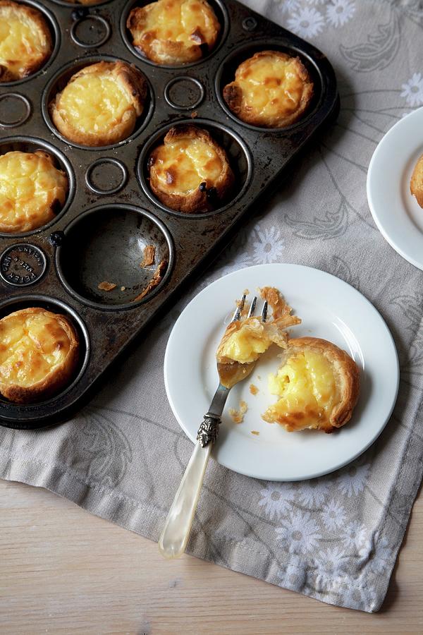 Portuguese Custard Tarts In A Baking Pan And On A Small White Plate With A Fork; From Above Photograph by Joy Skipper Foodstyling