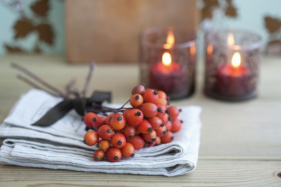 Posy Of Rose Hips; Two Painted, Glass Tealight Holders In Background Photograph by Martina Schindler