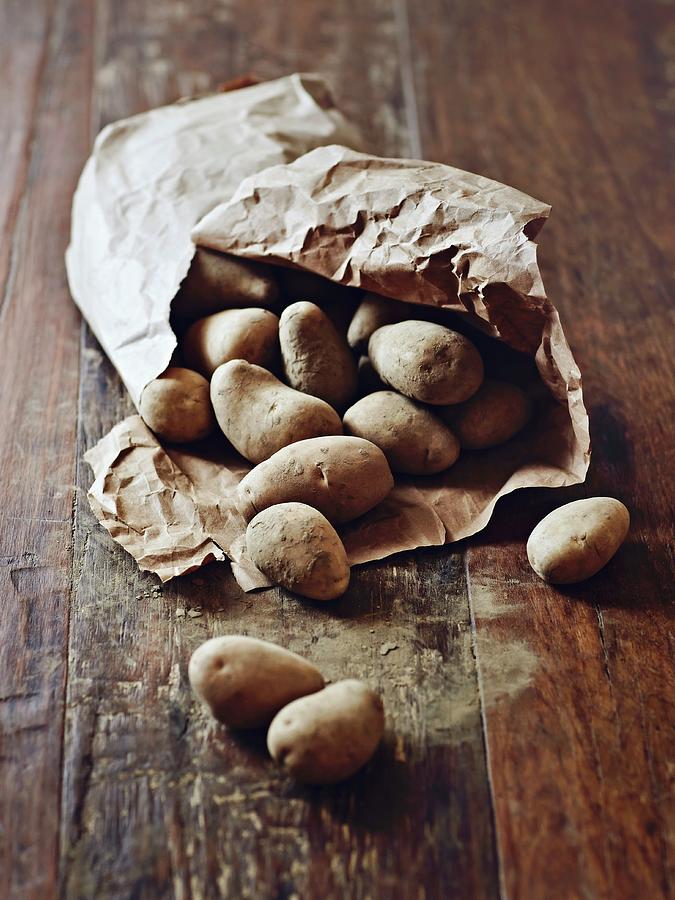 Potatoes In A Paper Sack On A Wooden Surface Photograph by Thorsten Kleine Holthaus