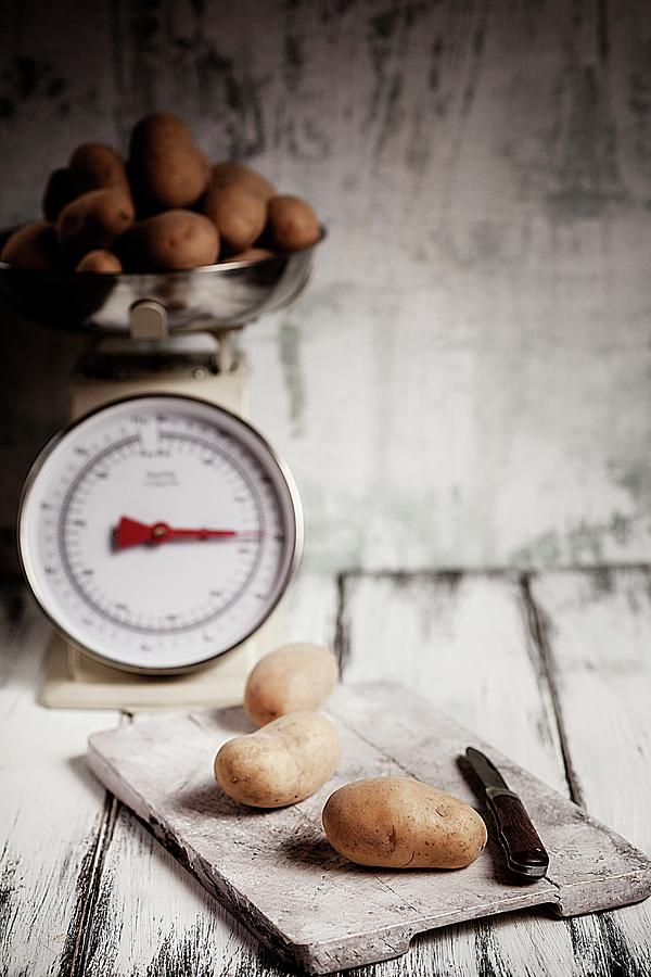 Potatoes On A Chopping Board And On An Old Pair Of Kitchen Scales Photograph by Susan Brooks-dammann