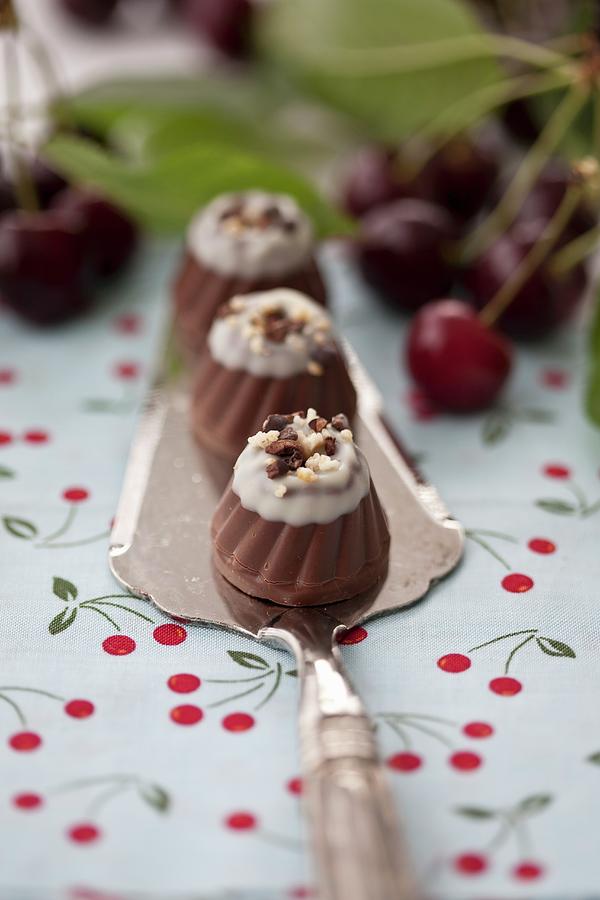 Pralines With Kirschwasser, Cherries And Cherry Leaves Photograph by Martina Schindler