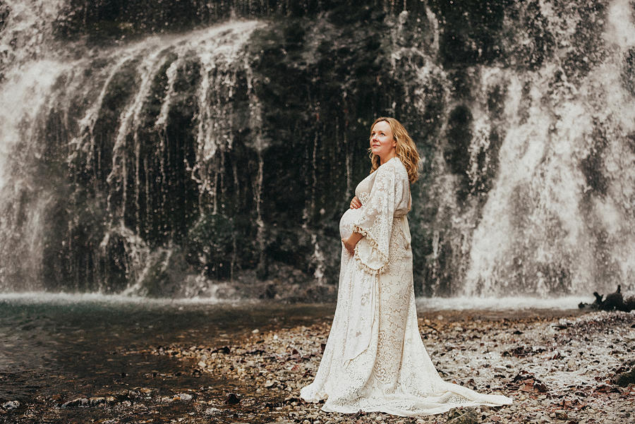 Parenthood Movie Photograph - Pregnant Woman Standing In Front Of Waterfall In Winter Touching Belly by Cavan Images
