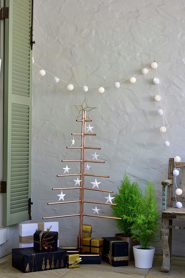 Presents Below Stylised Christmas Tree Made From Copper Piping And Decorated With Paper Stars Photograph by Great Stock!