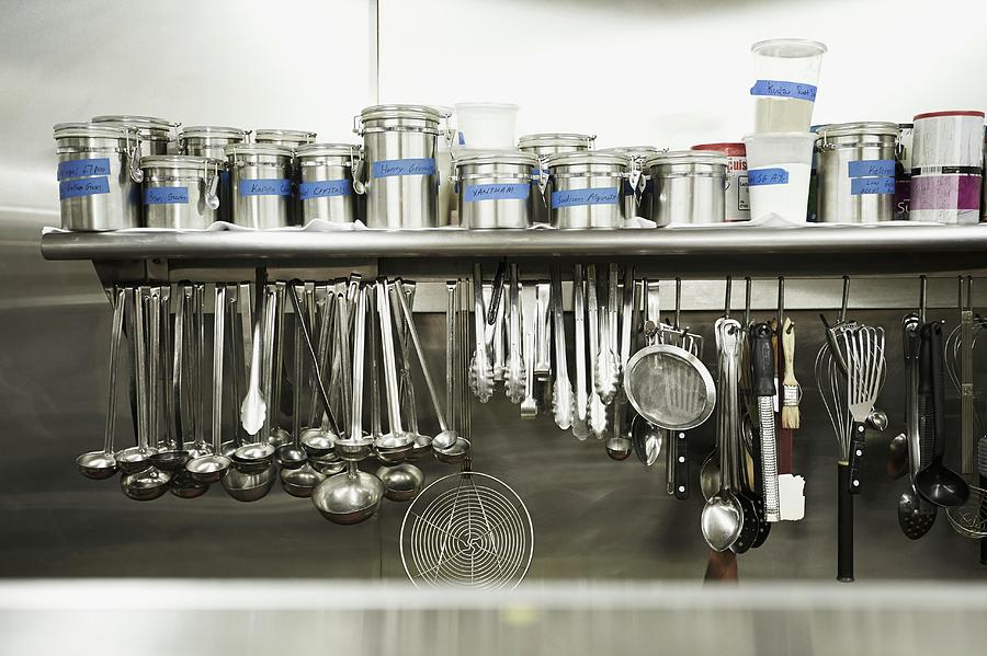 Professional Kitchen; Hanging Tools And Canisters Of Seasonings Photograph by Greg Rannells