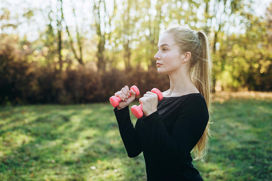 Sports Photograph - Profile Of Slim Girl With Dumbbells Outdoors. Fitness In Park. by Cavan Images